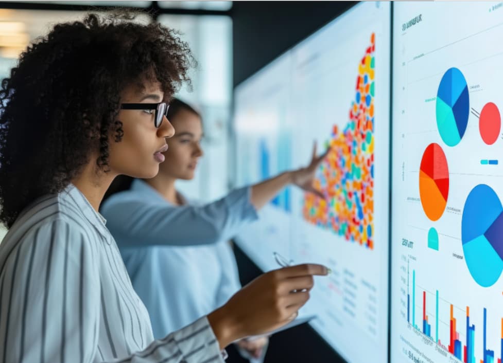 Two business professionals analyzing colorful data dashboards with charts and graphs, representing data-driven marketing decisions and measurable ROI from aligned sales and marketing systems.
